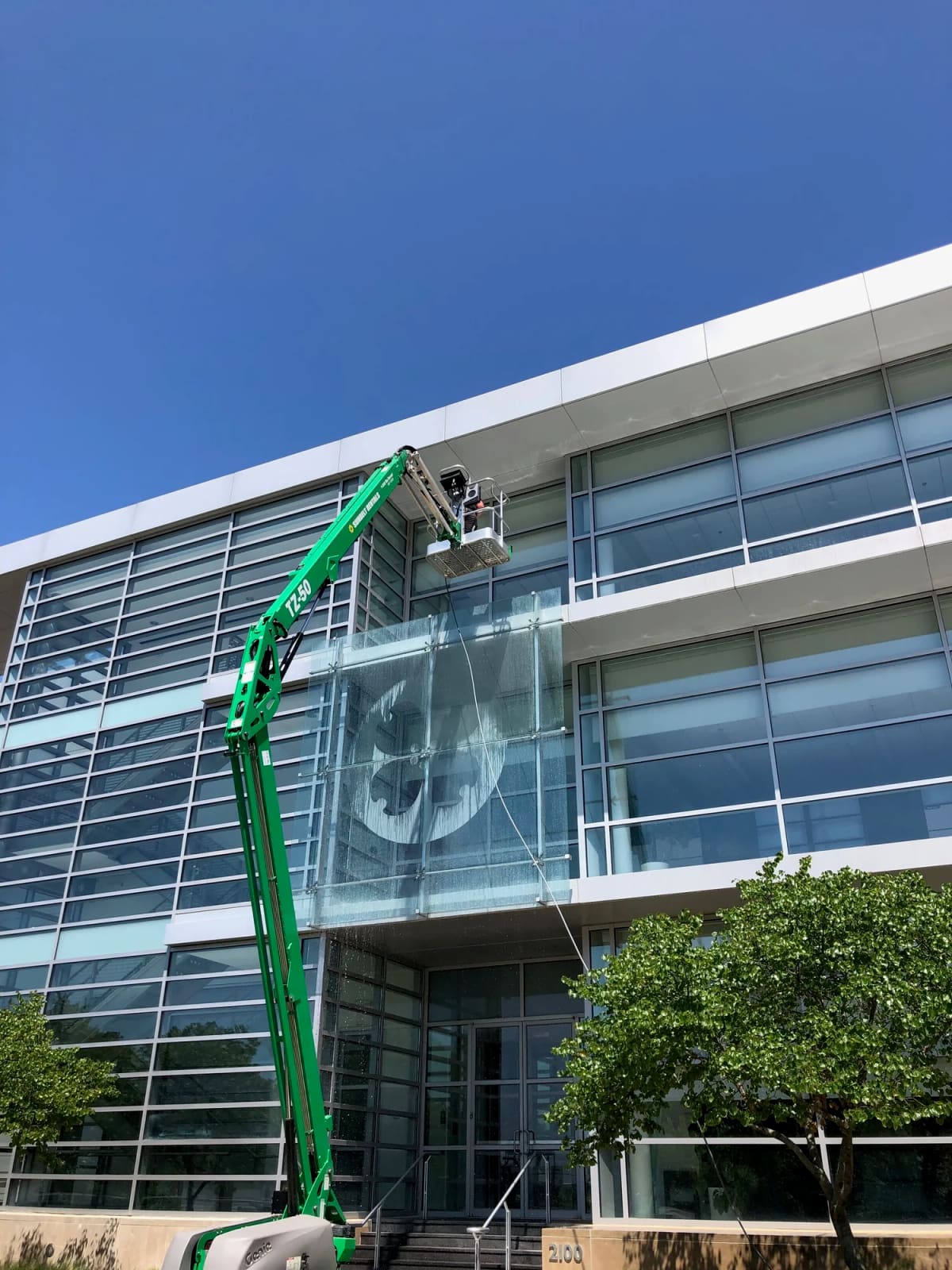 Crew on a lift washing the glass face of a multi-story office building