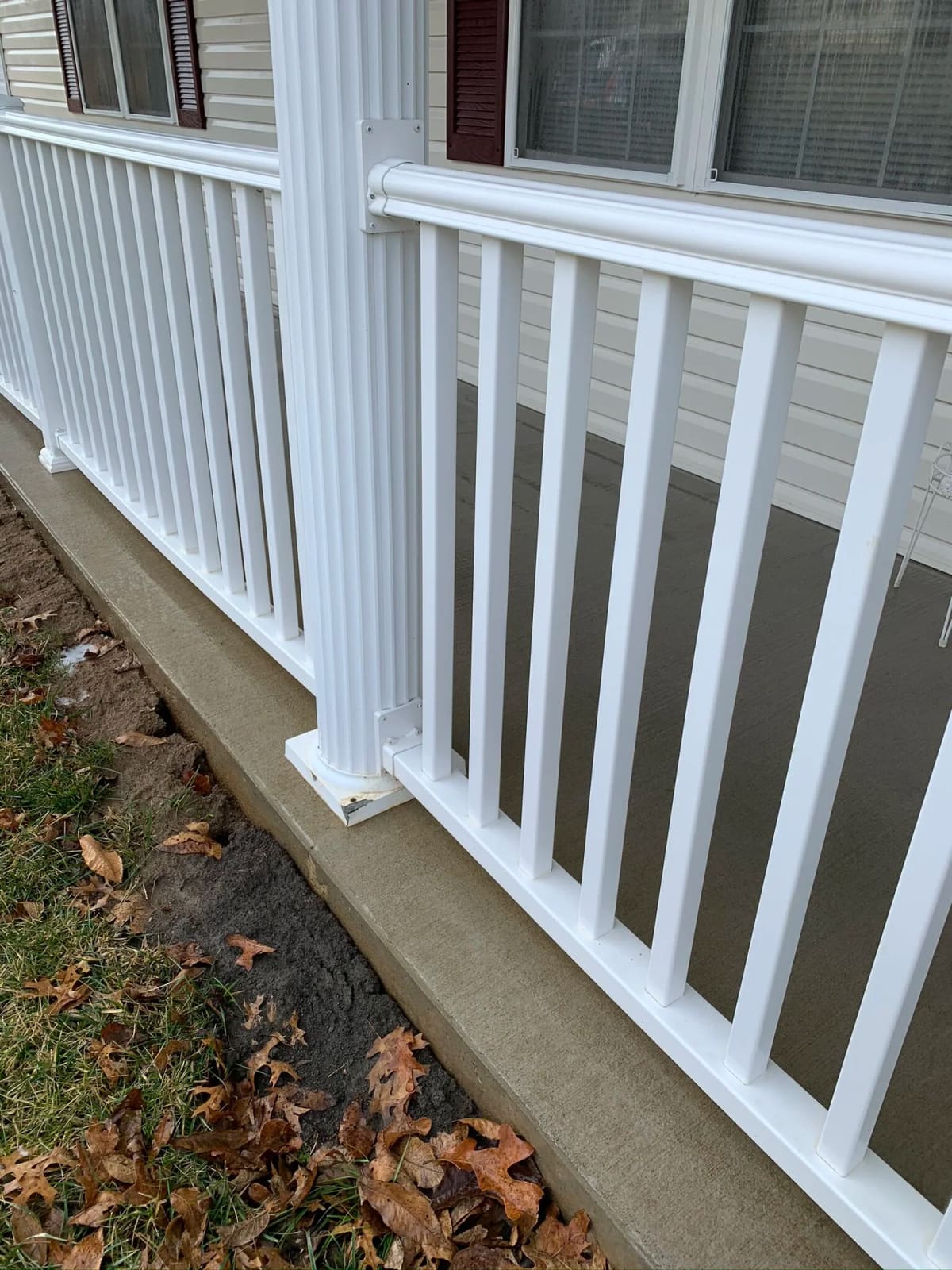 White porch railing and its base streaked with dirt before a soft wash