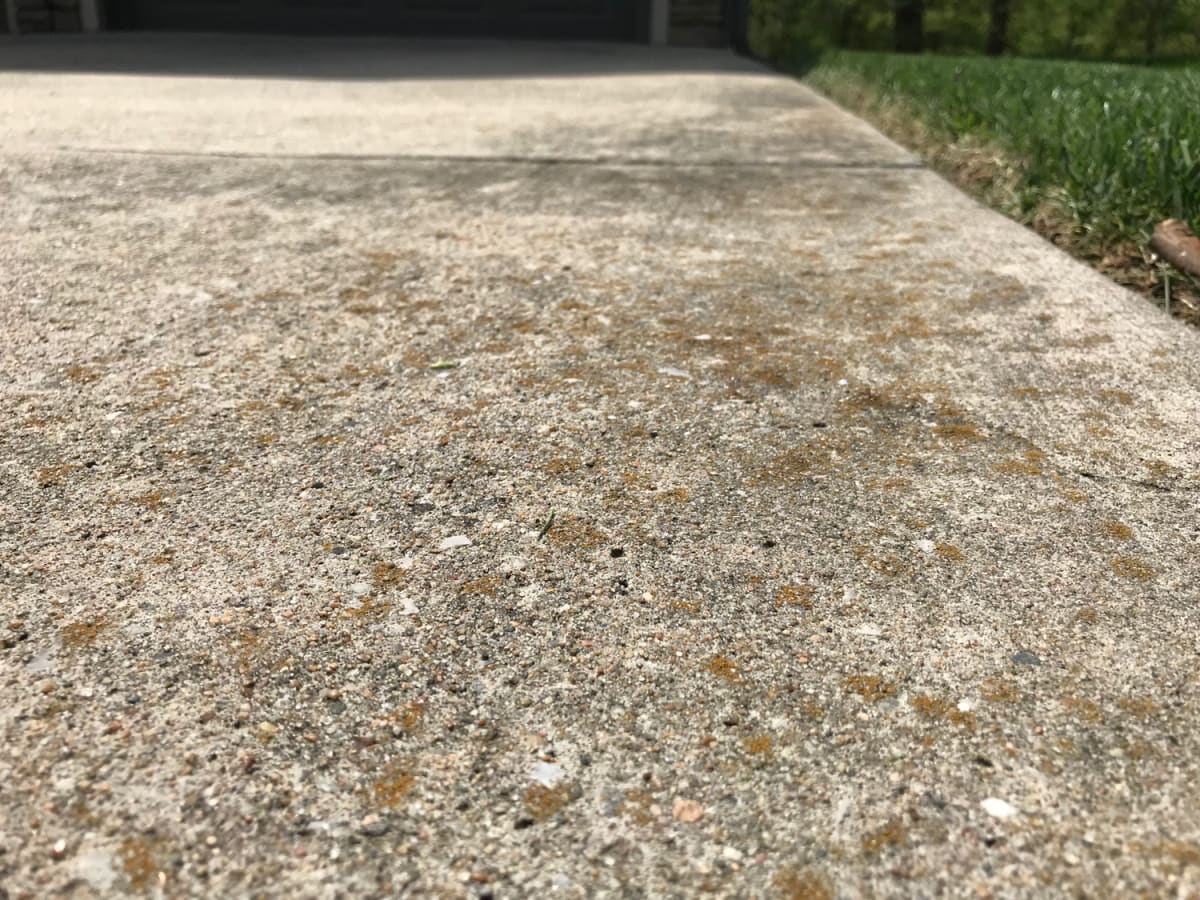 Concrete driveway with gray film and orange spotting before hot water concrete cleaning