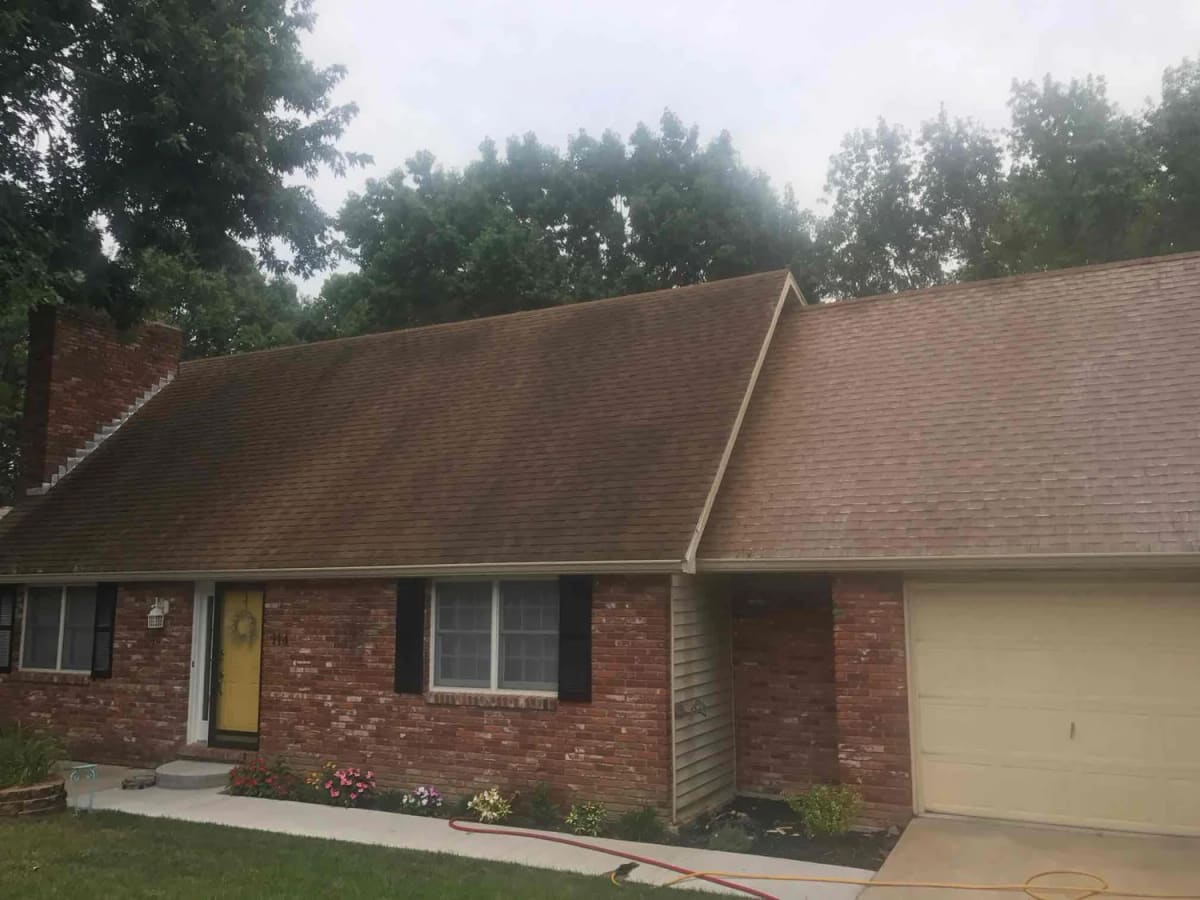 Brick ranch home with a dark streaked roof, dingy siding and dirty concrete before a full exterior clean