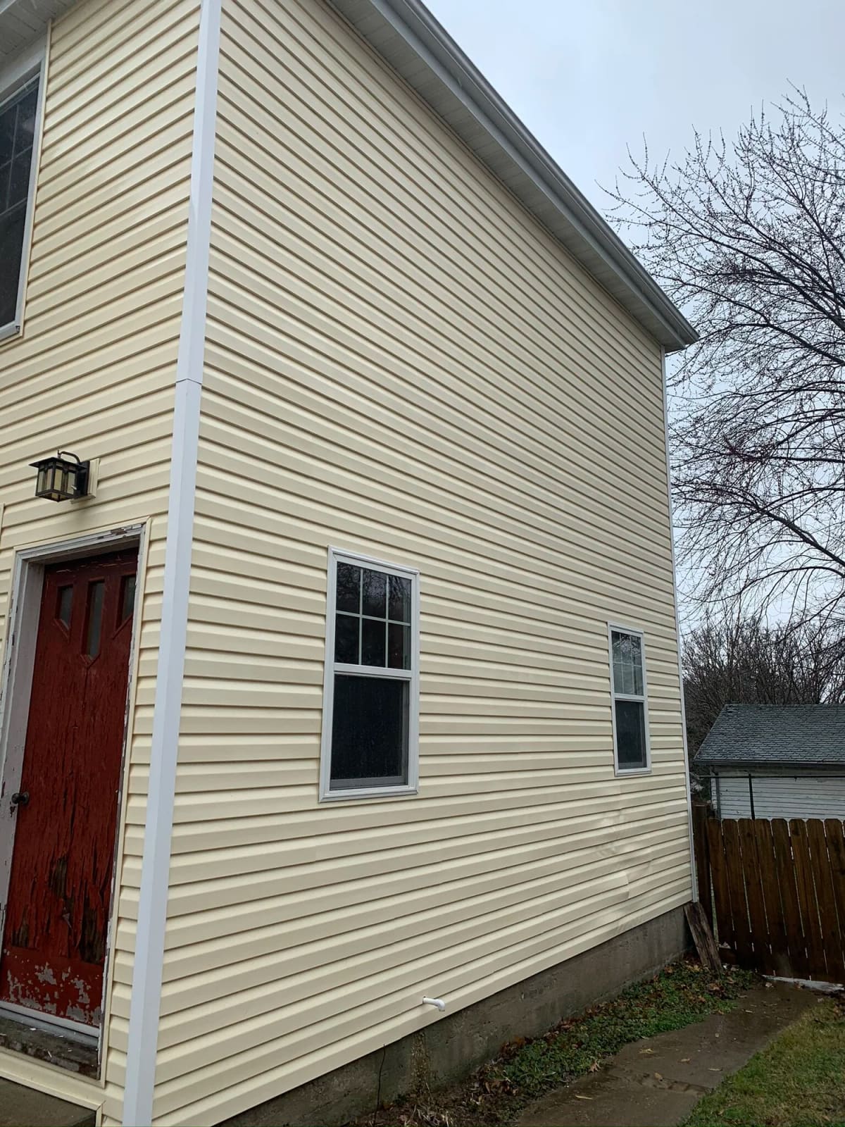 The same tan vinyl siding after soft wash house washing, the green growth gone