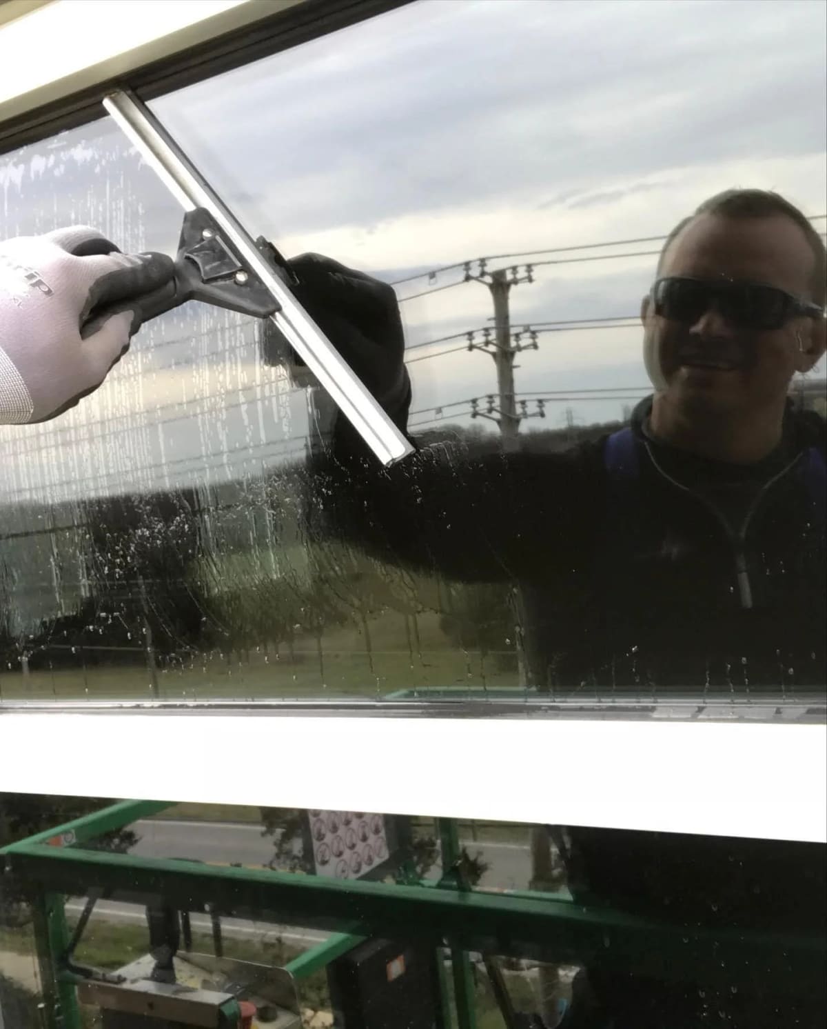 Squeegee pulling water off a window pane during window cleaning